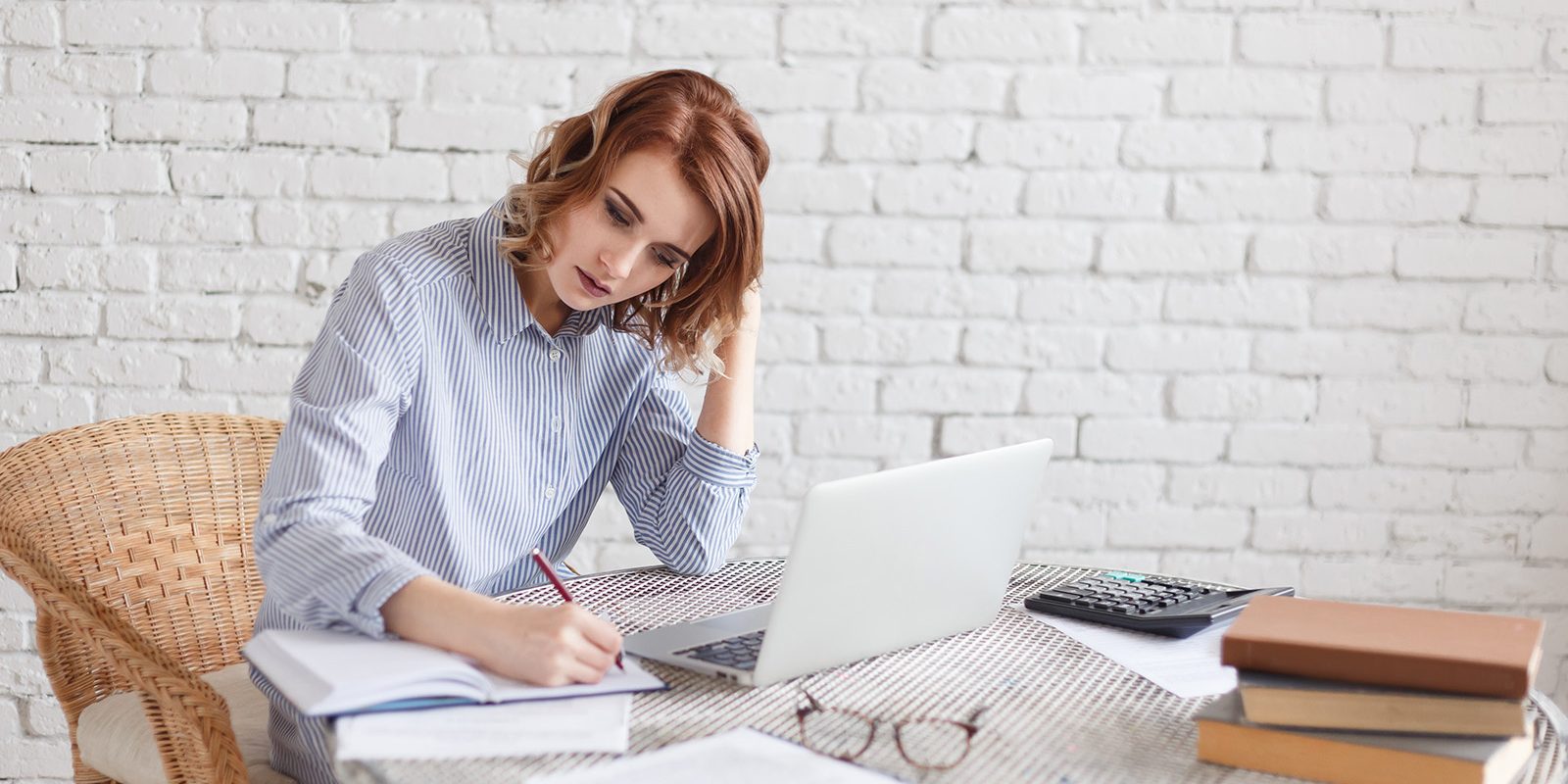 Woman freelancer female hands with pen writing on notebook at home or office